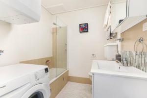 a bathroom with a washing machine and a sink at Stylish Apartment Close to Fox/Disney Studios in Centennial Park