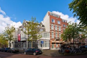 Un grand bâtiment avec des voitures garées devant lui dans l'établissement Leonardo Hotel Amsterdam City Center, à Amsterdam