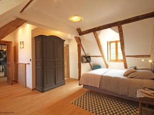 Un dormitorio con una cama y suelo de madera. en Longère percheronne de charme avec équipements modernes, jardin, terrasse, vélos gratuits et espace adapté PMR - FR-1-497-77, en Ceton