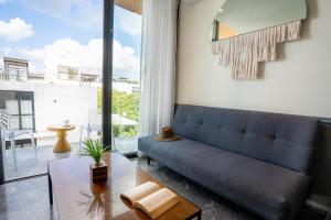 un salon avec un canapé bleu et une grande fenêtre dans l'établissement Singular by Andiani Travel, à Playa del Carmen