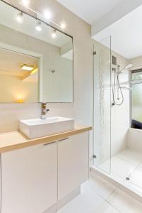 ein weißes Bad mit einem Waschbecken und einer Dusche in der Unterkunft Comfortable & stylish with rooftop spa in Sunshine Beach