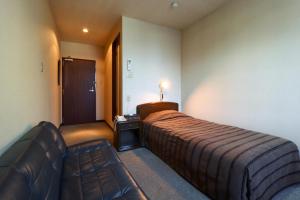 um quarto de hotel com uma cama e um sofá em Kobori Ryokan em Hirosaki