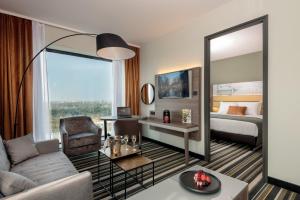 a living room with a couch and a bed and a mirror at Leonardo Royal Hotel Amsterdam in Amsterdam