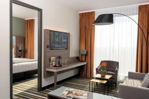 a hotel room with a bed and a desk and a mirror at Leonardo Royal Hotel Amsterdam in Amsterdam