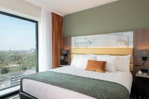 a hotel room with a bed and a large window at Leonardo Royal Hotel Amsterdam in Amsterdam