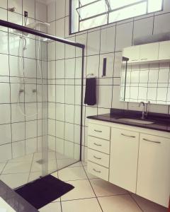 a white bathroom with a shower and a sink at Pousada & Hostel São Carlos in São Carlos