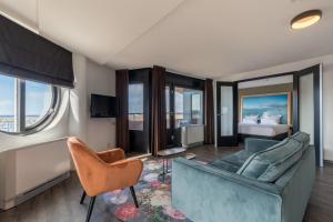 een woonkamer met een bank, stoelen en een bed bij Leonardo Hotel IJmuiden Seaport Beach in IJmuiden