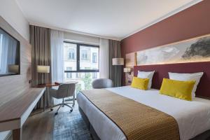 um quarto de hotel com uma cama, uma secretária e uma janela em Leonardo Hotel Antwerpen em Antuérpia
