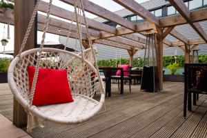 a hammock chair with a red pillow on a patio at Leonardo Hotel Papendrecht in Papendrecht