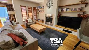 ein Wohnzimmer mit einem Sofa und einem TV in der Unterkunft Ice Chalet 2 in Thredbo