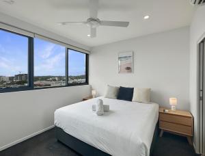 a bedroom with a white bed and a large window at Direct Collective - Rhythm on Beach in Maroochydore