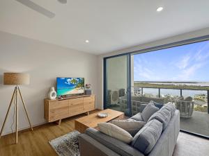 a living room with a couch and a large window at Direct Collective - Rhythm on Beach in Maroochydore