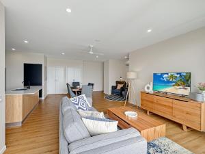 a living room with a couch and a tv at Direct Collective - Rhythm on Beach in Maroochydore