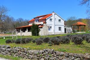 ein weißes Haus mit einer Steinmauer davor in der Unterkunft Villa Manuela in Hrvace