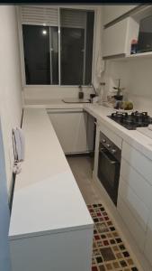 uma cozinha com balcões brancos e um forno com placa de fogão em Quarto privativo Interlagos autódromo em São Paulo