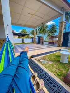 a person laying on a hammock in a house at Che Nonna Beach Homestay in Kampong Gebeng