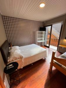 a bedroom with a bed and a large window at Pousada do Mel in Gramado