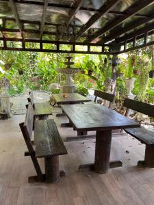 a group of wooden tables and benches in a pavilion at Wellness World Khao Yai in Ban Wang Sai