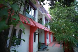 un edificio rojo y blanco con árboles delante de él en LA CASA THE HOMESTAY, en Trivandrum