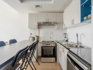 a kitchen with white cabinets and a counter with chairs at 3BDRM Near Metro for Family&Group in Dubai