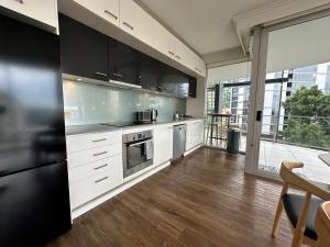 cocina con armarios blancos y nevera negra en Story Apartments, en Brisbane