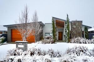 a house in the snow with a garage at Pinecone Lodge - Luxury 4BR Home l EV Charger l Fire Pit l WiFi l BBQ l 4 Car Garage in Jindabyne