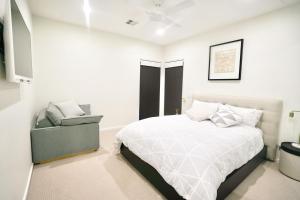 a white bedroom with a bed and a chair at Pinecone Lodge in Jindabyne
