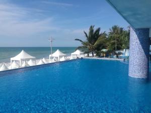 a swimming pool next to the ocean with white umbrellas at Apartment (Grand Diamond Beach) Tonsupa in Tonsupa