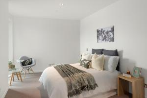 a white bedroom with a bed and a desk at Clearwater Quays Apartments in Christchurch