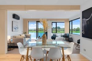 uma sala de estar com uma mesa de vidro e cadeiras brancas em Clearwater Quays Apartments em Christchurch