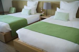 2 camas con sábanas verdes y blancas en una habitación en gran terrace Le Lien Hakone en Hakone