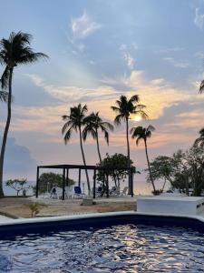 a swimming pool next to a beach with palm trees at Hotel Villa Mexicana Puerto Escondido in Puerto Escondido