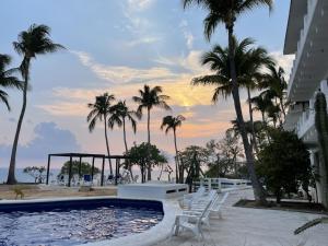 a pool with chairs and palm trees in front of a building at Hotel Villa Mexicana Puerto Escondido in Puerto Escondido