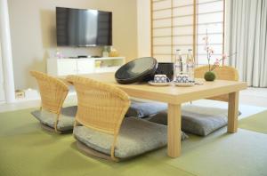 una mesa de madera con sillas y una sala de estar con TV. en gran terrace Le Lien Hakone en Hakone
