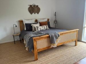 uma cama de madeira com almofadas num quarto em Casa Rossi - coastal gem only 300 metres from the beautiful Red Rocks beach - Cowes, Phillip Island em Cowes