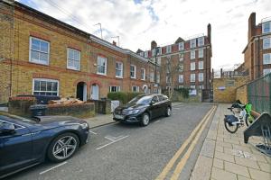 two cars parked on a street in front of buildings at Comfy 4 bed house close to station and theatre in London