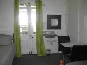 1 dormitorio con cortinas verdes, lavamanos y 1 cama en Australian Hotel Winton Budget Hotel Accommodation, en Winton