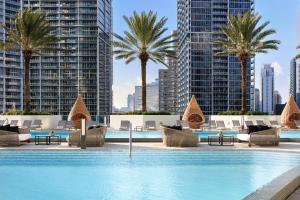 a pool with chairs and palm trees and buildings at Kimpton EPIC Hotel by IHG in Miami