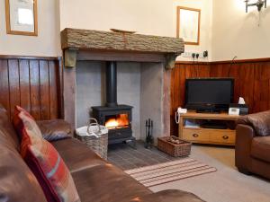 a living room with a fireplace and a tv at Lealholme in Bassenthwaite