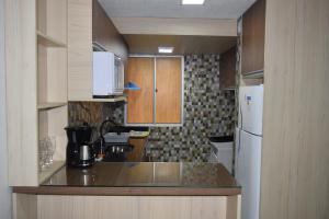 uma cozinha com armários de madeira e um frigorífico branco em APARTAMENTO 2 QUARTOS COMPLETAMENTE MOBILIADO COM GARAGEM em São Borja