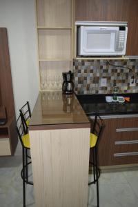 uma cozinha com um balcão com cadeiras e um micro-ondas em APARTAMENTO 2 QUARTOS COMPLETAMENTE MOBILIADO COM GARAGEM em São Borja