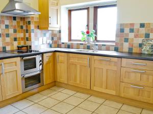 a kitchen with wooden cabinets and a stove at The Wagon House in Wellow