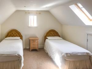 a attic bedroom with two beds and a window at The Wagon House in Wellow