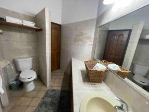 y baño con aseo y lavabo con espejo. en Casa Orta Ensenada, en Ensenada