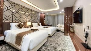 a hotel room with two beds and a television at Cửa Đông Luxury Hotel in Vinh