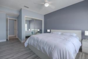 a white bedroom with a large white bed and a mirror at Sea La Vie Beach Oceanfront Patio Pet Friendly in Jacksonville Beach