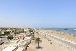 索哈尔مارينا للغرف الفندقية的享有棕榈树海滩和建筑的景色