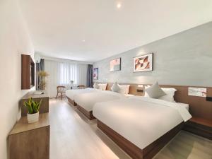 JianyangにあるHoliday Inn Guoshangのベッド3台とテーブルが備わるホテルルームです。