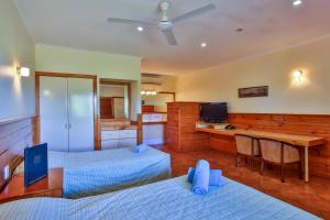 a hotel room with a bed, desk and a television at Kimberley Hotel in Halls Creek