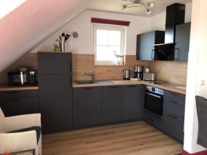 a kitchen with black cabinets and a sink at Ferienwohnung "Möwe" im Ferien-Resort Rügen in Sagard